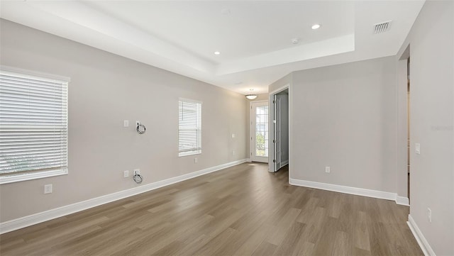 spare room with visible vents, baseboards, a tray ceiling, recessed lighting, and wood finished floors