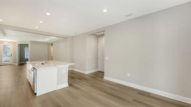 kitchen featuring visible vents, a sink, a center island with sink, light wood-style floors, and stainless steel dishwasher