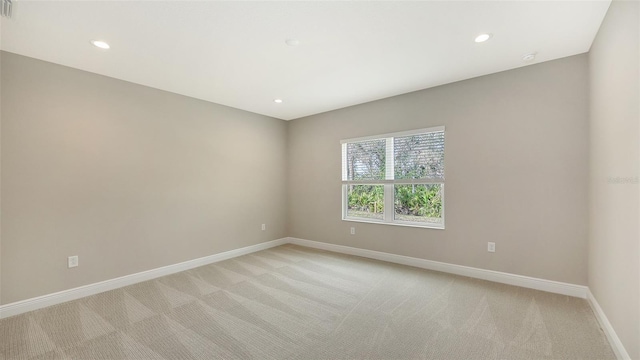 empty room featuring visible vents, recessed lighting, light colored carpet, and baseboards