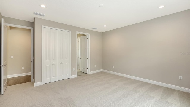 unfurnished bedroom with a closet, recessed lighting, light colored carpet, and baseboards