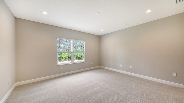 spare room with recessed lighting, light colored carpet, visible vents, and baseboards