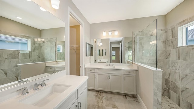 bathroom featuring two vanities, walk in shower, and a sink