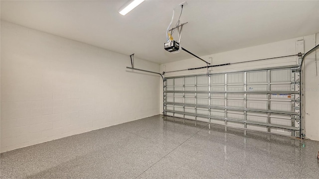 garage featuring a garage door opener and concrete block wall