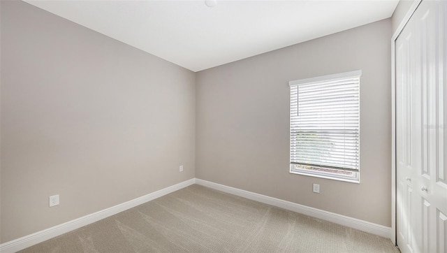 unfurnished room featuring baseboards and light carpet