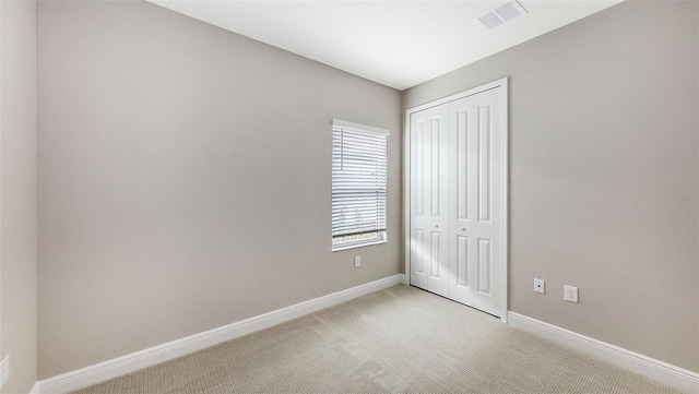 unfurnished bedroom featuring baseboards, visible vents, a closet, and light carpet