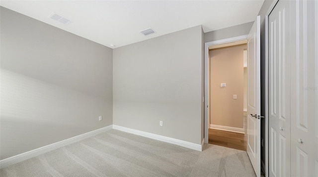 unfurnished bedroom featuring visible vents, baseboards, light colored carpet, and a closet