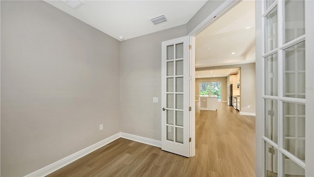 unfurnished room with french doors, baseboards, visible vents, and wood finished floors