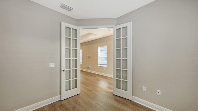 spare room featuring french doors, baseboards, visible vents, and wood finished floors