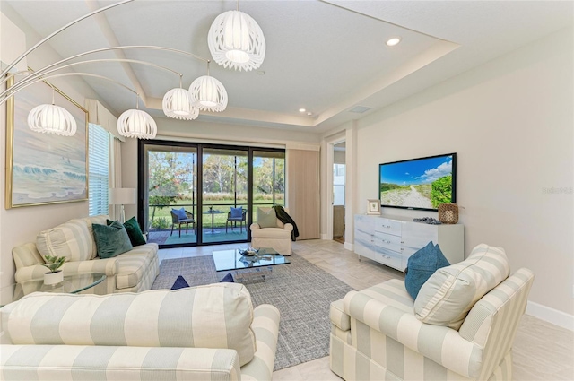 living room featuring a raised ceiling, recessed lighting, baseboards, and a chandelier