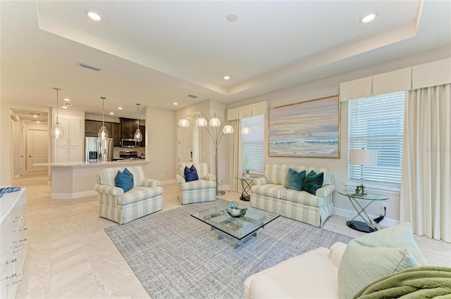 living area featuring recessed lighting, a tray ceiling, baseboards, and visible vents