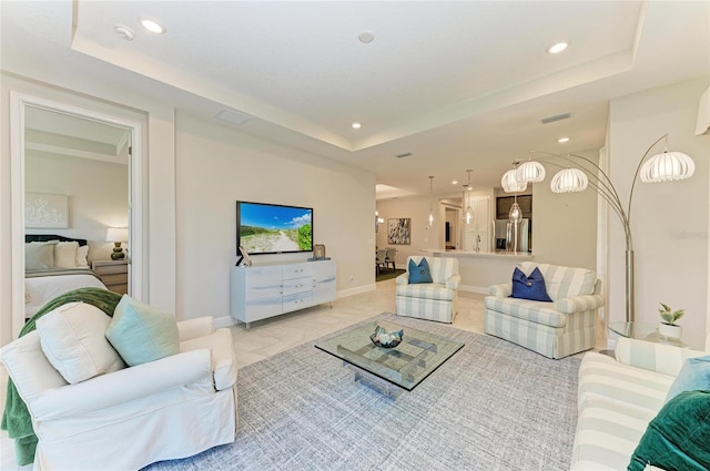 living room with a raised ceiling, recessed lighting, visible vents, and baseboards