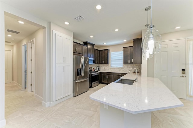 kitchen with visible vents, dark brown cabinets, appliances with stainless steel finishes, a peninsula, and a sink