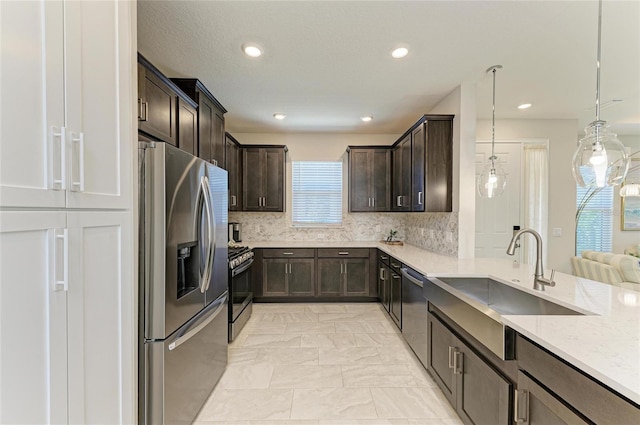 kitchen featuring a sink, tasteful backsplash, dark brown cabinetry, appliances with stainless steel finishes, and light stone countertops