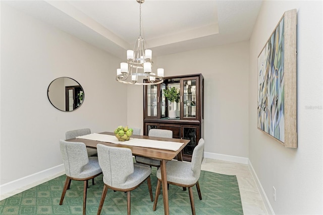 dining space with an inviting chandelier, a raised ceiling, and baseboards