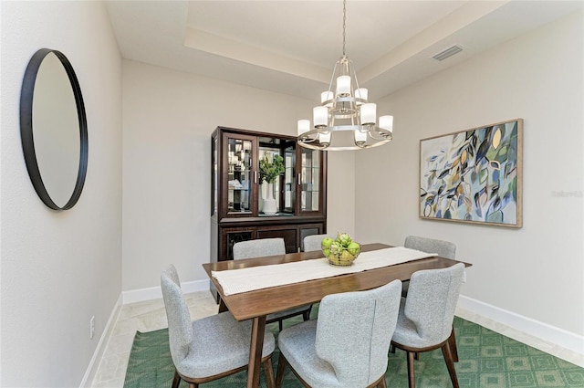 dining room featuring visible vents, a raised ceiling, a notable chandelier, and baseboards