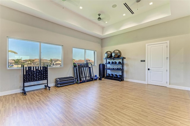 workout room with a raised ceiling, wood finished floors, baseboards, and ceiling fan