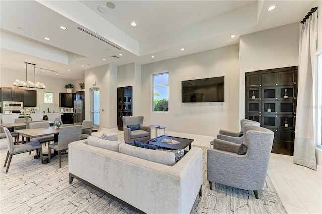 living room featuring a notable chandelier, recessed lighting, baseboards, and a tray ceiling