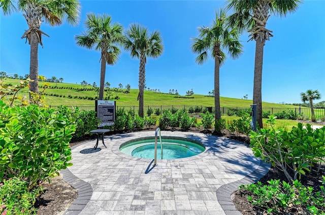 view of swimming pool featuring a rural view, fence, and a hot tub