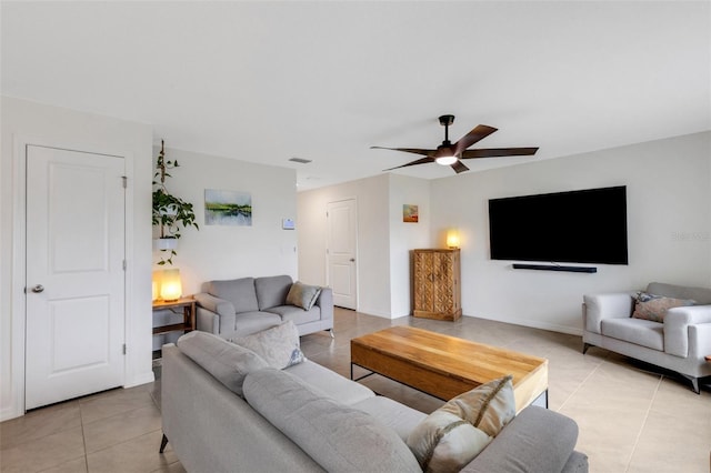 living area with light tile patterned floors, a ceiling fan, and baseboards