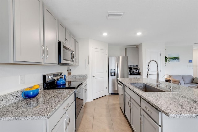 kitchen with visible vents, a sink, gray cabinetry, stainless steel appliances, and a kitchen island with sink