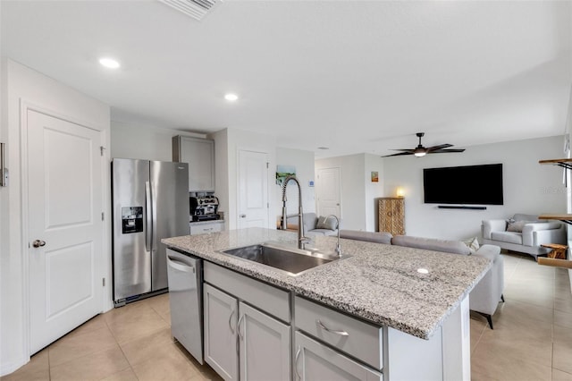 kitchen with light tile patterned floors, visible vents, a center island with sink, a sink, and stainless steel appliances