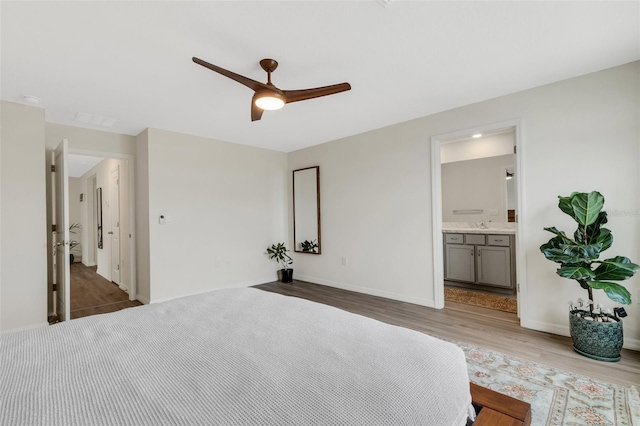 bedroom featuring connected bathroom, ceiling fan, baseboards, and wood finished floors