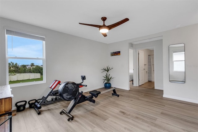 exercise room featuring a ceiling fan, baseboards, and light wood-type flooring