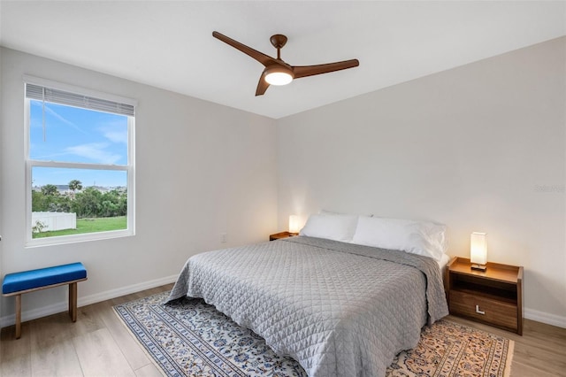 bedroom with light wood-style flooring, a ceiling fan, and baseboards