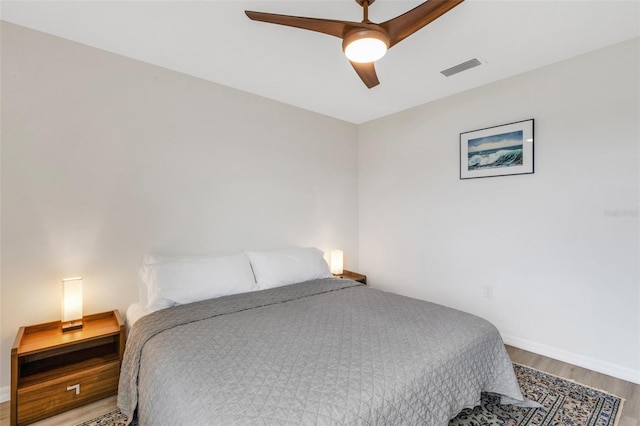 bedroom with a ceiling fan, wood finished floors, visible vents, and baseboards