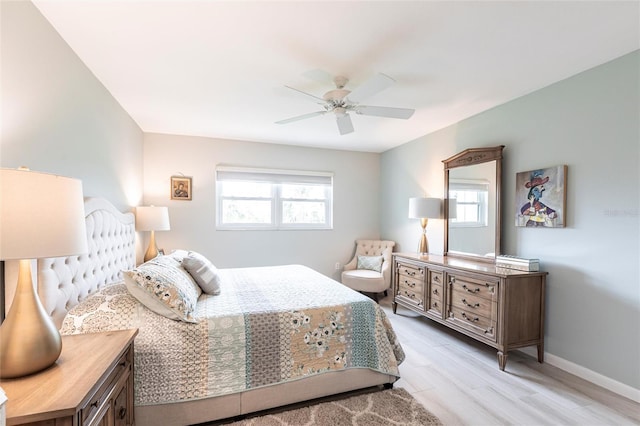 bedroom with multiple windows, baseboards, light wood finished floors, and ceiling fan