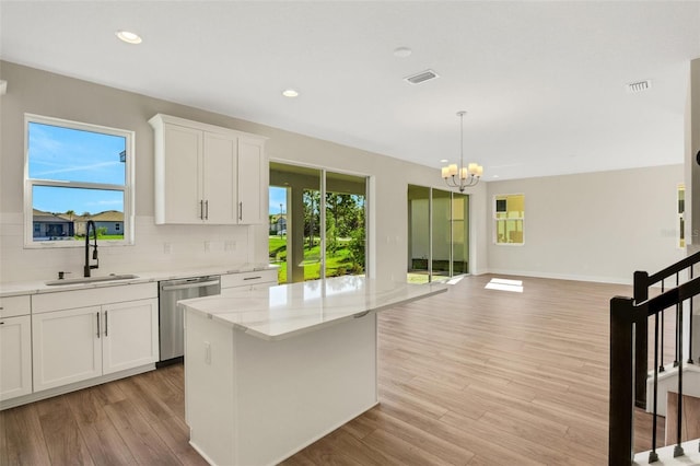 kitchen featuring visible vents, backsplash, a sink, light wood-style floors, and stainless steel dishwasher