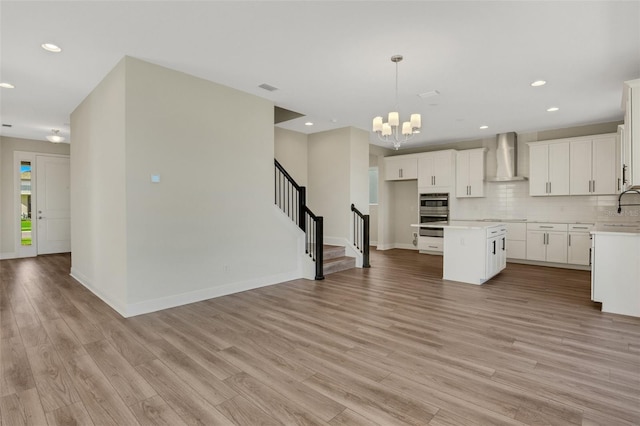 kitchen with wall chimney exhaust hood, tasteful backsplash, and light wood-type flooring