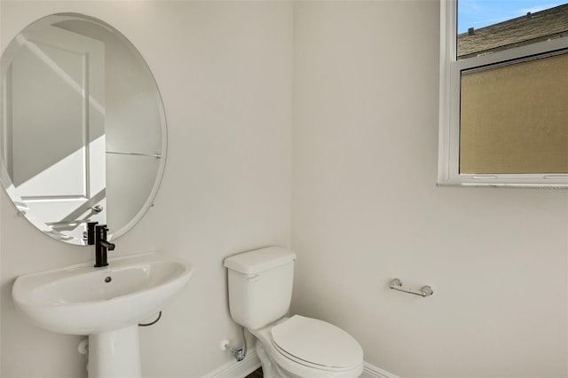 bathroom with a sink, baseboards, and toilet