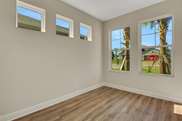 spare room featuring baseboards and wood finished floors