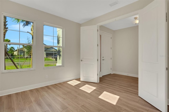 unfurnished room featuring light wood finished floors, visible vents, and baseboards