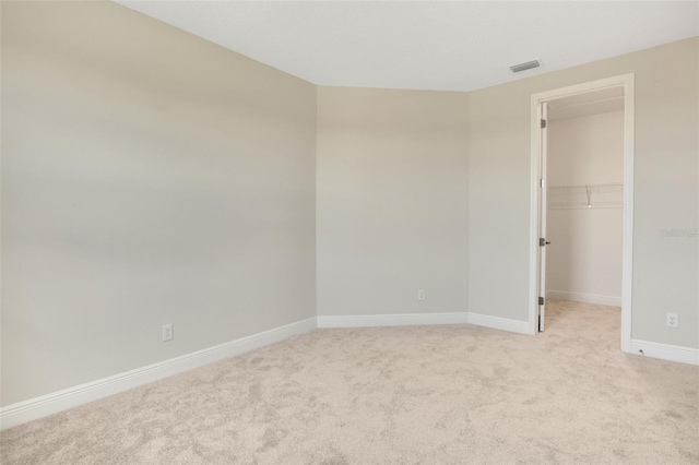 spare room with baseboards, visible vents, and light carpet