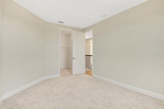 unfurnished room with visible vents, light carpet, and baseboards