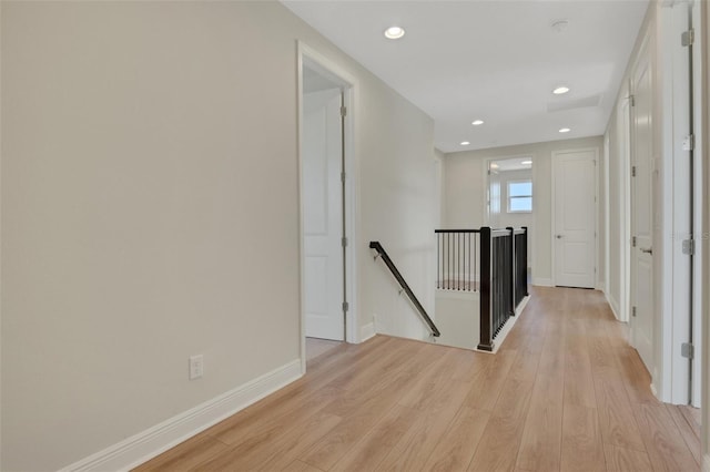 hallway featuring recessed lighting, baseboards, an upstairs landing, and light wood finished floors