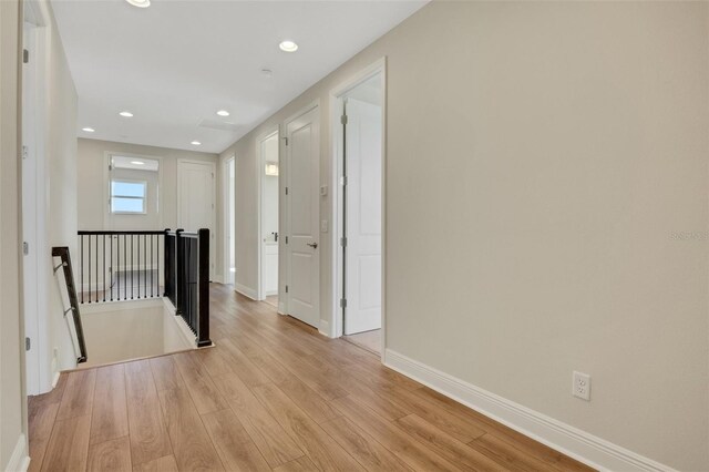 corridor with recessed lighting, an upstairs landing, light wood-style floors, and baseboards