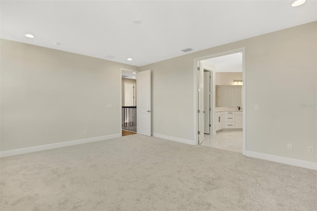 unfurnished bedroom featuring visible vents, baseboards, light colored carpet, recessed lighting, and ensuite bath