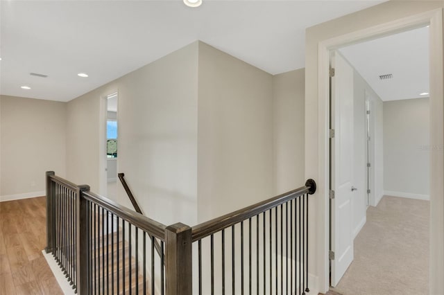 hall featuring visible vents, baseboards, light wood-style flooring, recessed lighting, and an upstairs landing