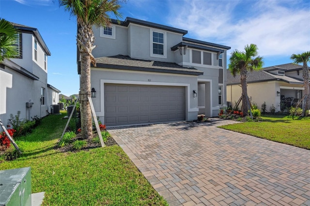 prairie-style home with stucco siding, decorative driveway, a garage, and a front lawn