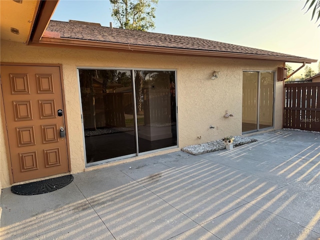 exterior space with a patio, roof with shingles, and stucco siding