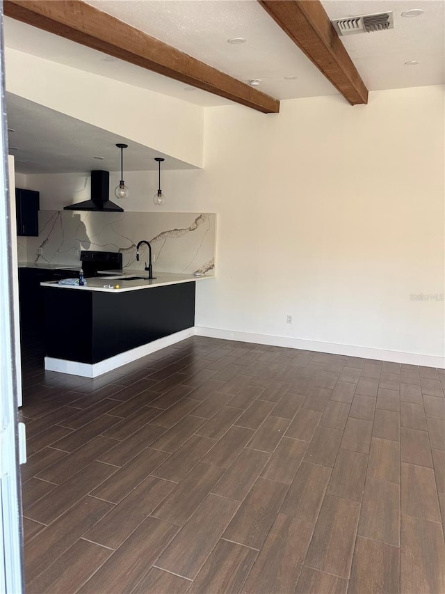 kitchen featuring visible vents, wood finish floors, light countertops, beam ceiling, and range hood