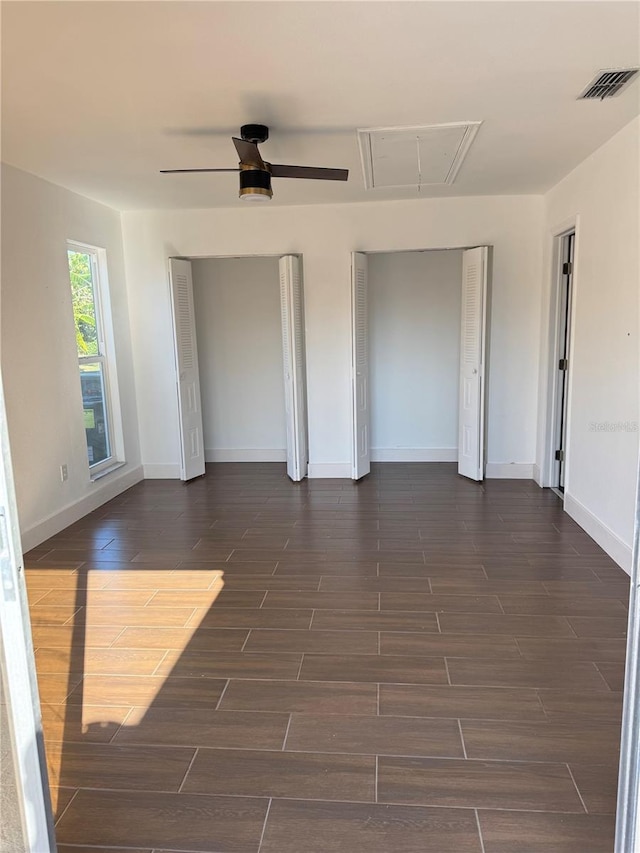 empty room featuring baseboards, visible vents, attic access, and wood finish floors