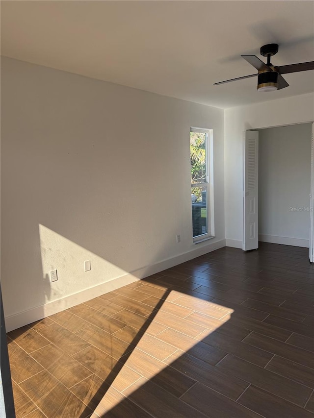 unfurnished room with baseboards, dark wood-type flooring, and ceiling fan