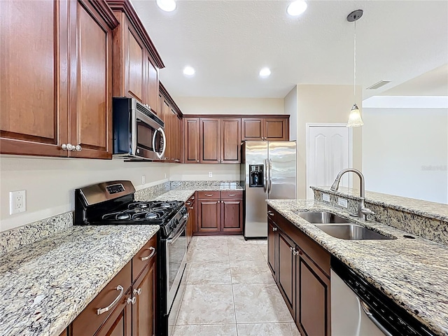 kitchen featuring visible vents, a sink, light stone counters, stainless steel appliances, and hanging light fixtures