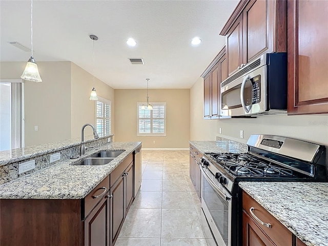 kitchen with light stone countertops, visible vents, a sink, stainless steel appliances, and decorative light fixtures