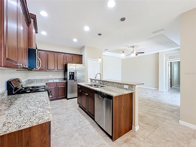 kitchen with an island with sink, ceiling fan, a sink, appliances with stainless steel finishes, and pendant lighting