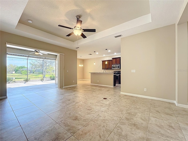 unfurnished living room featuring a tray ceiling, baseboards, visible vents, and a textured ceiling